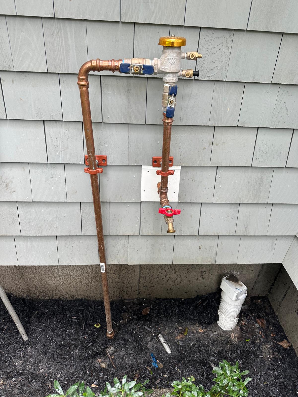 Backflow preventer assembly installed on a home exterior in Greater Boston, MA